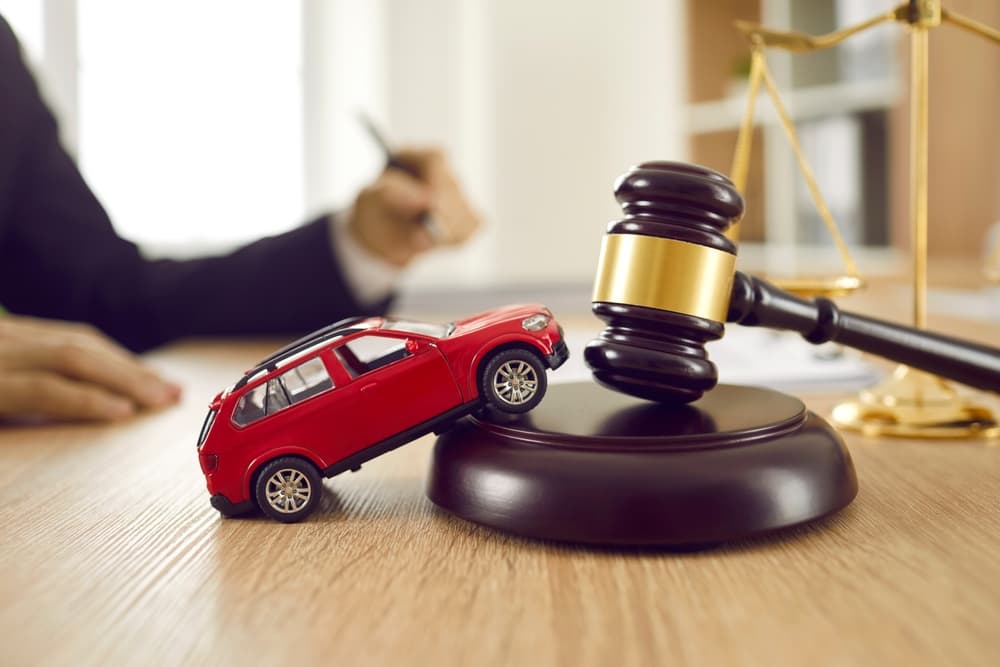 Red toy car on a judge's gavel, symbolizing legal proceedings in traffic cases.