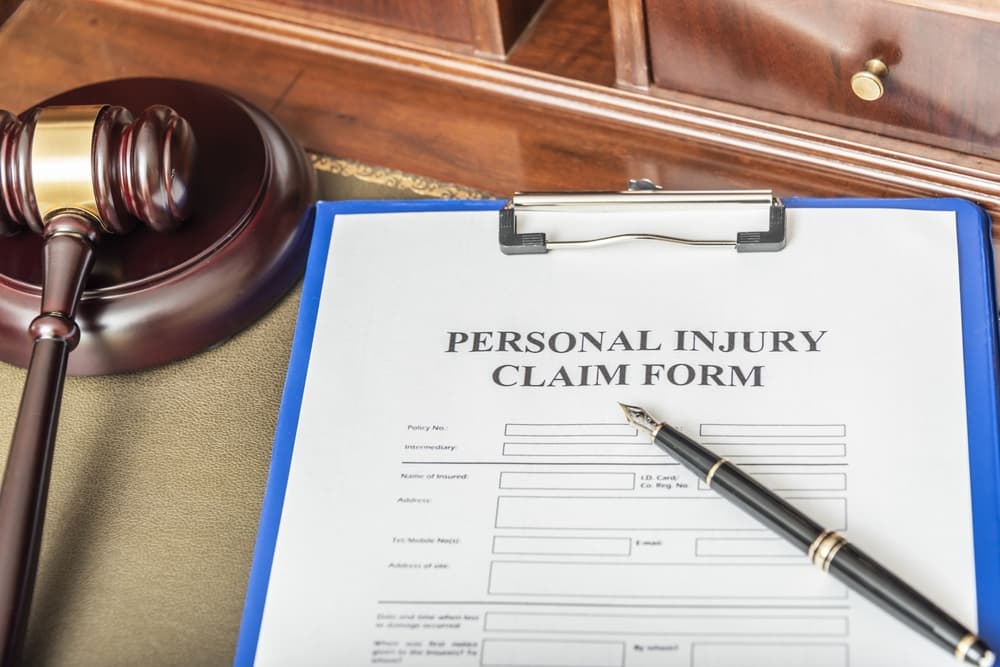 Personal injury claim form on clipboard with gavel in a legal office setting.