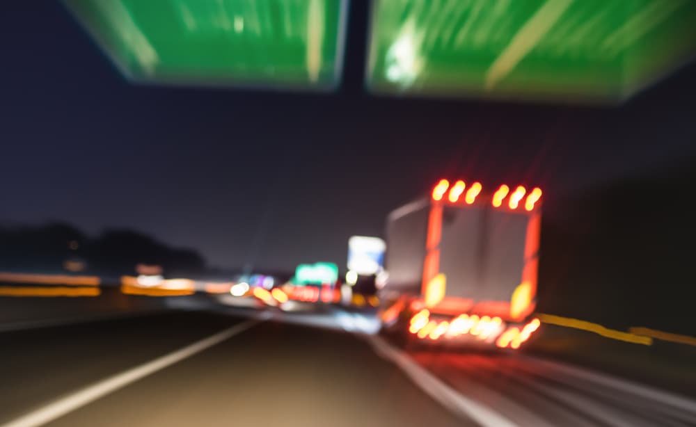 Blurred image of a truck on a highway at night, symbolizing the danger of truck accidents.