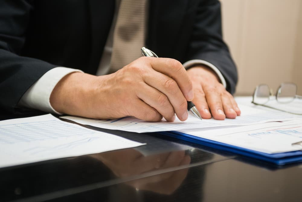 Businessman reviewing and writing on a document related to a truck accident claim, focused on gathering details and preparing for legal action.