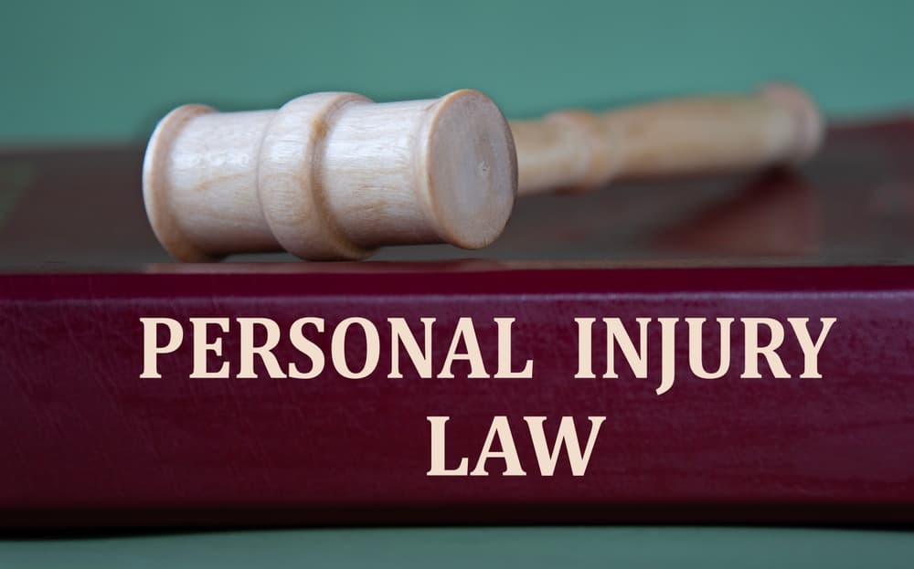 The words "PERSONAL INJURY LAW" are printed on a burgundy folder, placed against the background of a judge's gavel.