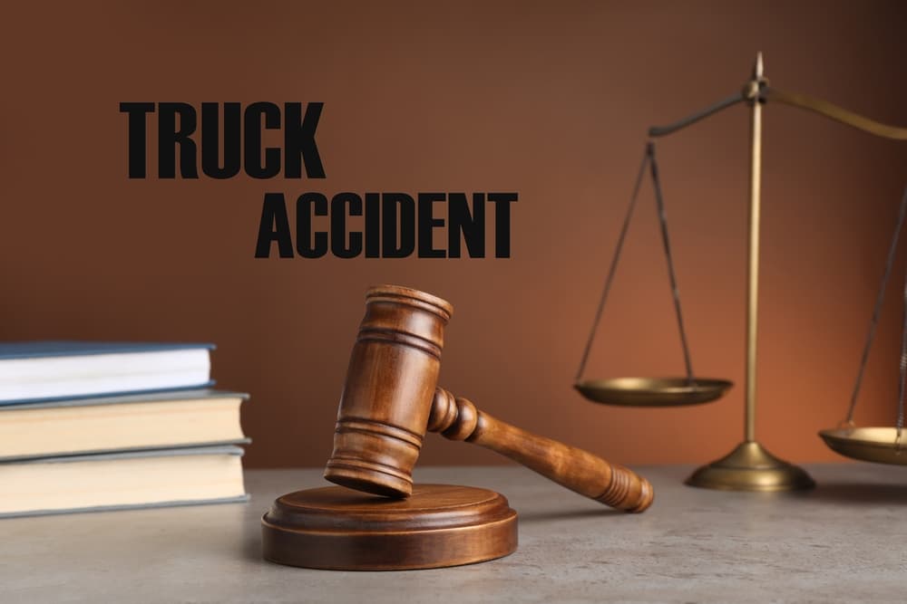 Truck accident law concept with a judge's gavel, scales of justice, and law books on a table, set against a rich brown background.