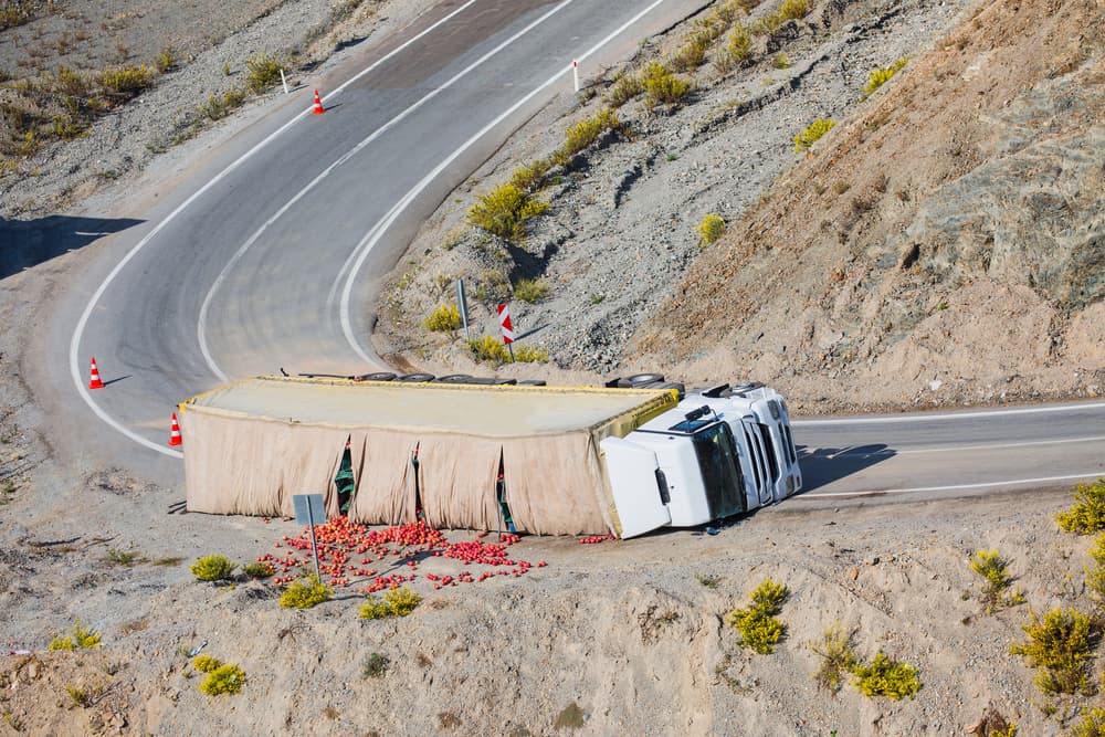 A cargo truck overturned, lying across the road after the incident.