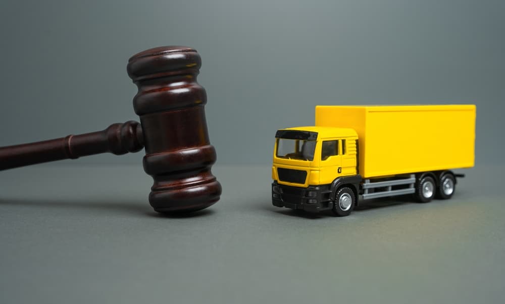 Yellow truck and judge's gavel symbolizing a court case involving new laws, restrictions, and regulations.